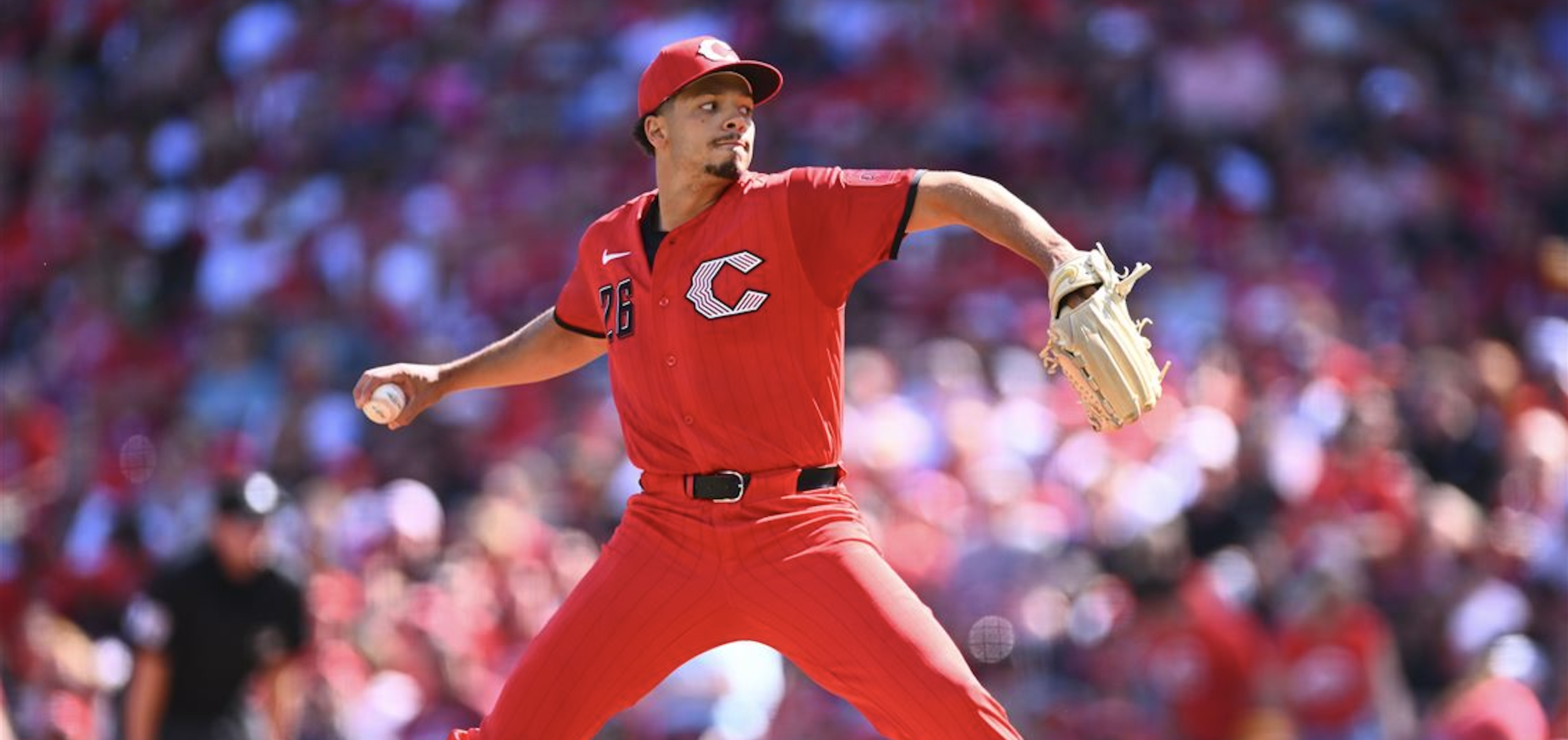 Chase Burns delivering a pitch in his red Reds uniform at Great American Ball Park