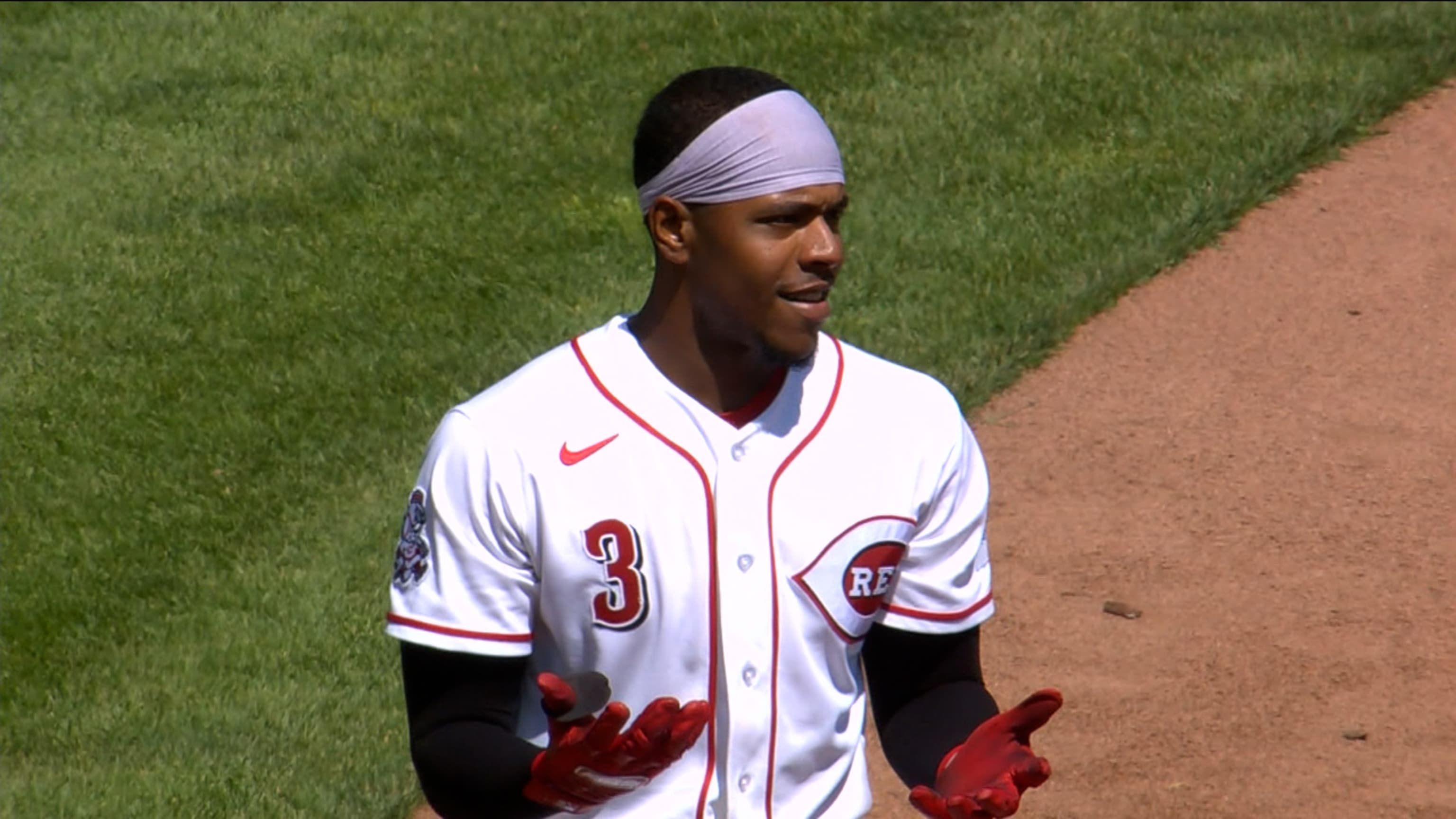 Ke'Bryan Hayes standing on the basepath in his white Reds home jersey, hands turned up in a shrug, gray headband, after a flyout
